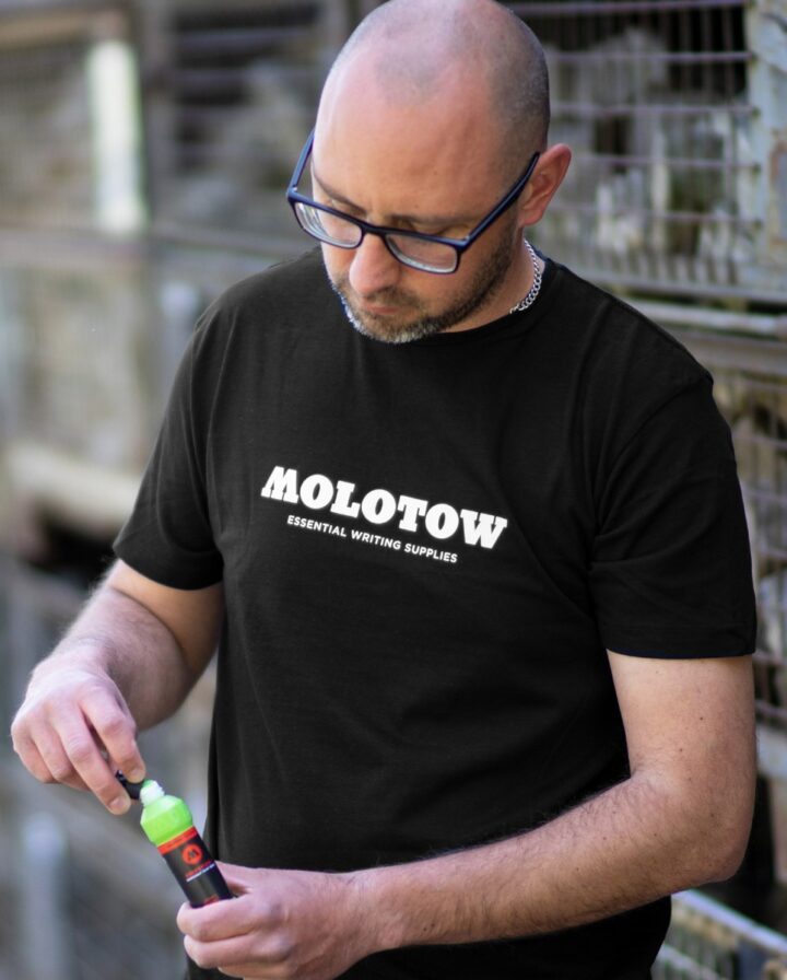 PETA-approved Fairwear: ein veganes schwarzes T-Shirt mit MOLOTOW™ Aufdruck in weiß getragen von einem Mann