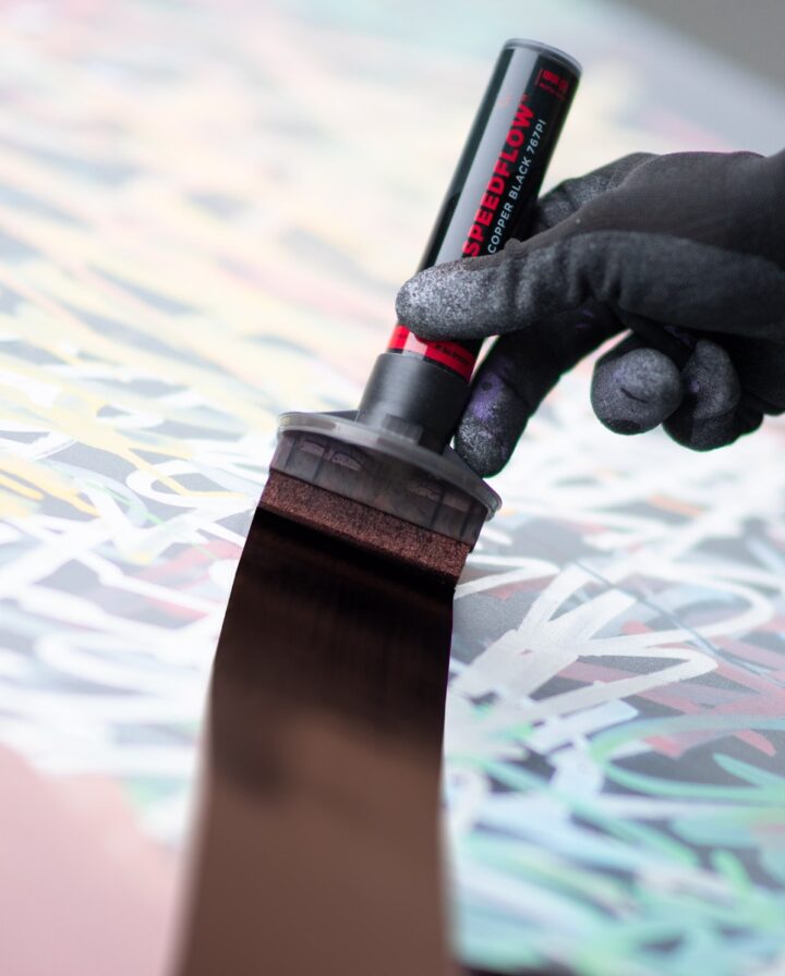 Hand with glove and very broad pen paints over graffiti